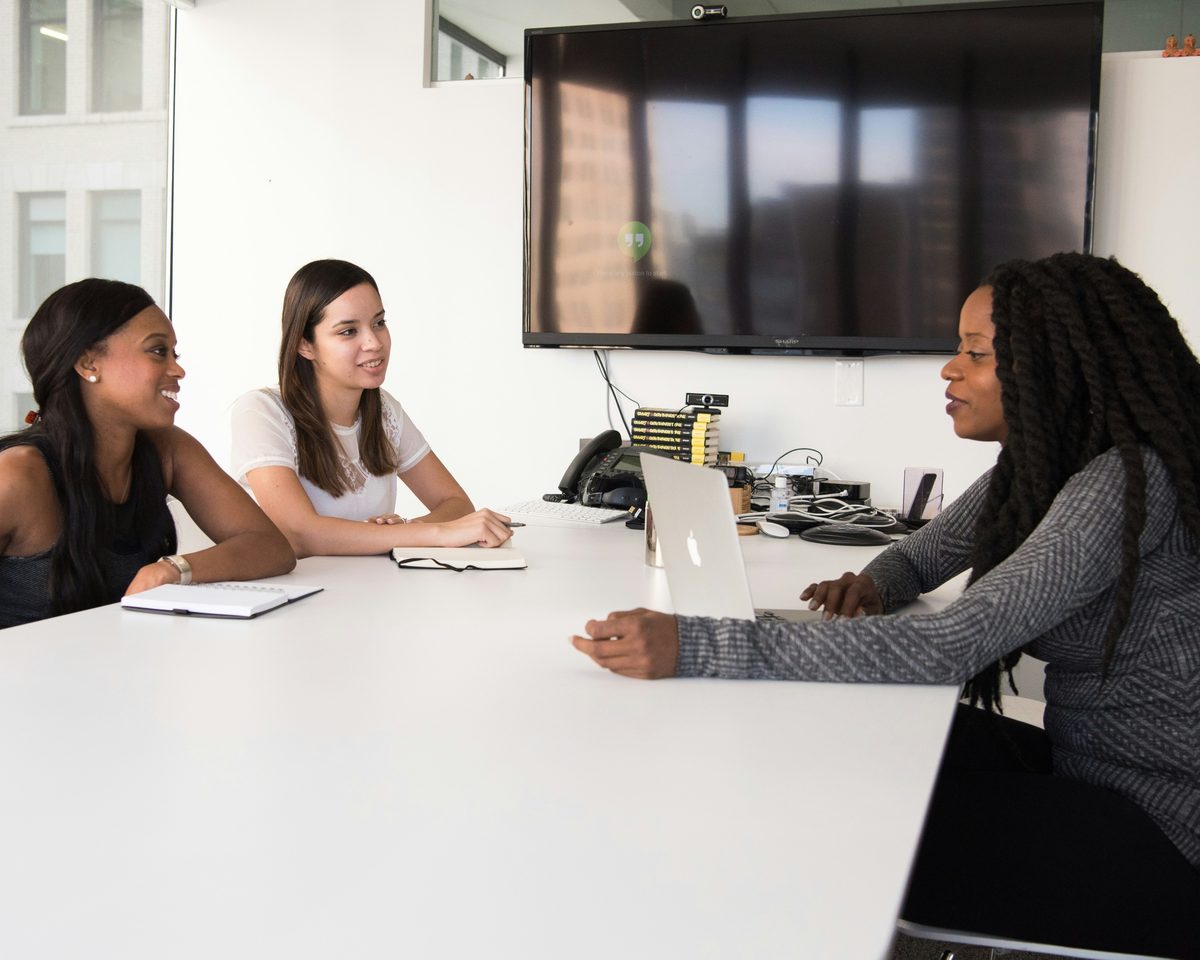 An HR specialist and a colleague in conversation with a hiring manager at a meeting table