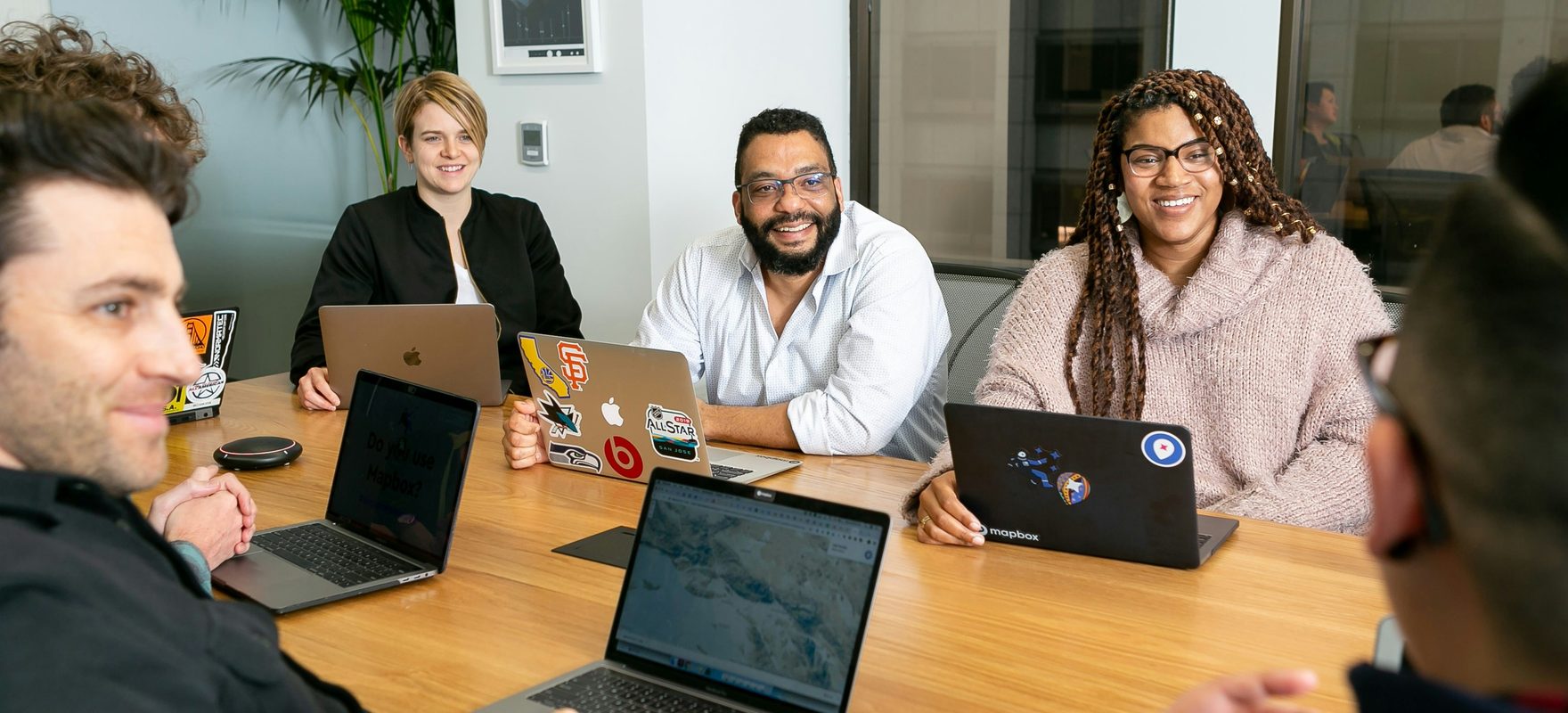 A cross-functional team collaborating around a table with laptops